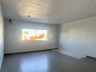 Ambiente interno de uma sala ampla com piso de porcelanato e grande janela.