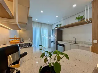 Vista da cozinha moderna com armários brancos e bancadas claras.