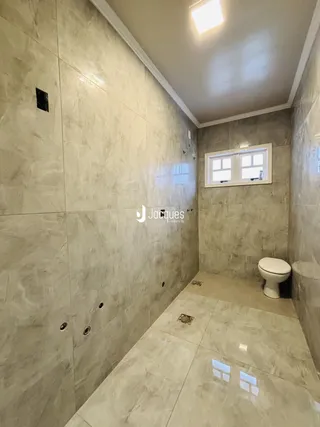 Foto de um banheiro com revestimento de azulejos claros.