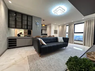 Sala de estar com sofá escuro e janela com vista para a cidade.