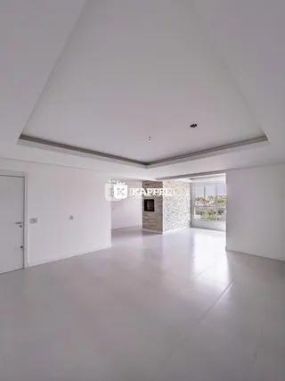 Sala ampla com piso claro e parede de destaque de tijolos em um imóvel em Lajeado.