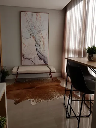 Sala de estar com uma pintura abstrata e cortinas claras.