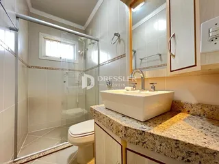 Foto de um banheiro com box de vidro e louças sanitárias.