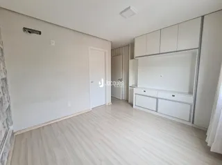 Ambiente interno de uma sala com piso de madeira clara e paredes brancas.