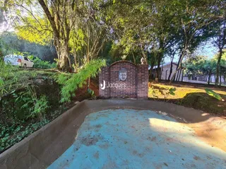 Vista externa de um terreno com muro de tijolos e vegetação.
