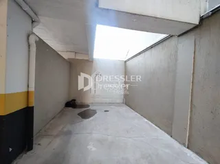 Corredor interno com piso de concreto e paredes simples.
