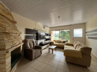 Sala de estar com lareira de pedra e sofá claro.