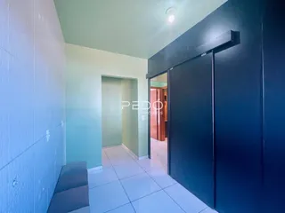 Hall de passagem com paredes verde-claro e piso de cerâmica branca.
