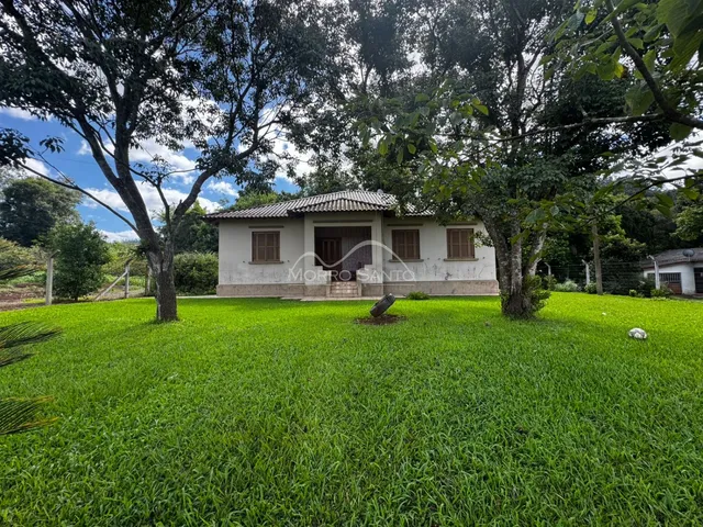 A fachada de uma casa em Lajeado, Brasil, cercada por um grande gramado e árvores.
