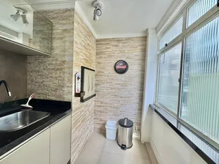 Foto da cozinha mostrando a bancada escura e o revestimento da parede clara.