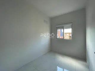 Ambiente interno de uma sala com piso claro e paredes brancas.