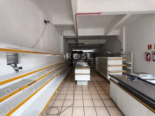 Interior de um espaço com estantes longas e piso de cerâmica.