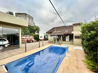 Foto de uma piscina externa com deck de madeira em um quintal.
