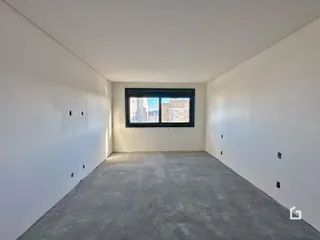 Imagem de um cômodo vazio com paredes brancas e piso de concreto.