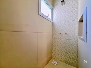 Foto de um interior com paredes revestidas de azulejos brancos e uma janela.