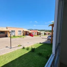 Vista externa do terreno com gramado e edifícios residenciais ao fundo.