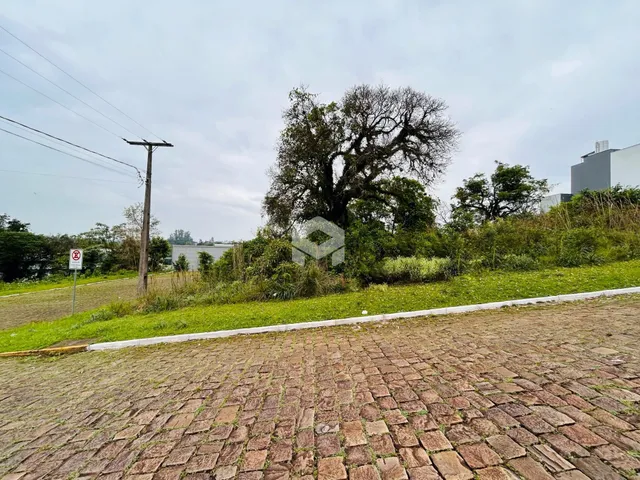 Foto da fachada de uma propriedade com área pavimentada e vegetação ao fundo.