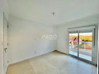 Uma sala de estar clara com piso de cerâmica e porta de vidro.