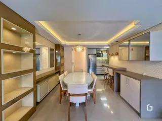 Uma sala de jantar moderna conectada a uma cozinha com armários embutidos.
