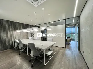 Sala ampla com mesa de trabalho e cadeiras em um ambiente iluminado.