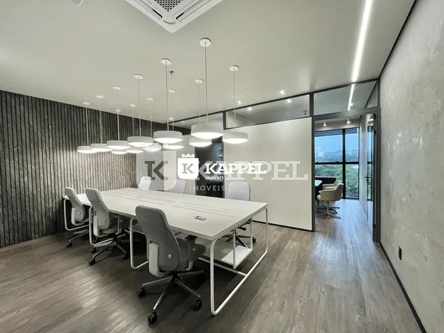 Sala ampla com mesa de trabalho e cadeiras em um ambiente iluminado.