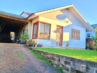 Fachada de uma casa em Lajeado, Brasil, com jardim e muro de pedra.