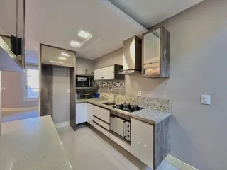Cozinha moderna com armários brancos e bancadas de granito claro.