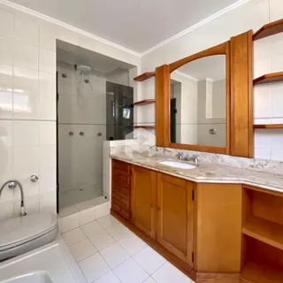 Foto de um banheiro com revestimento branco e bancada de madeira.