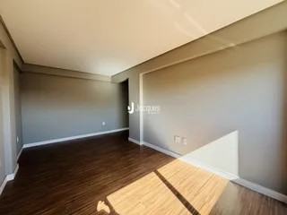 Ambiente interno de uma sala com piso de madeira e paredes cinzas.