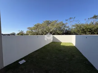 Vista de um quintal gramado cercado por um muro branco.