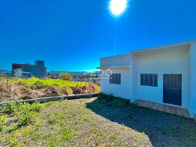 Fachada de uma residência branca em Lajeado, Brasil, com gramado em primeiro plano.