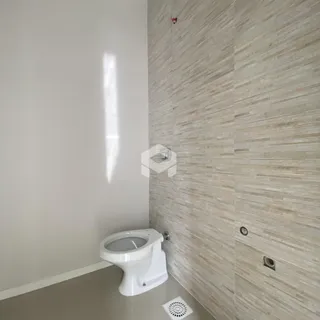 Banheiro com revestimento de parede em tons claros e piso branco.