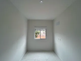 Interior de uma sala com paredes brancas e piso de cerâmica.