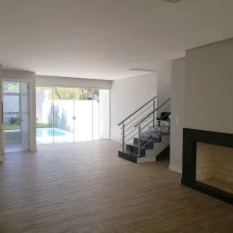 Sala de estar com piso de madeira e teto branco em um imóvel.