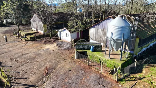 Vista aérea de uma propriedade rural com celeiros de madeira e um silo metálico.