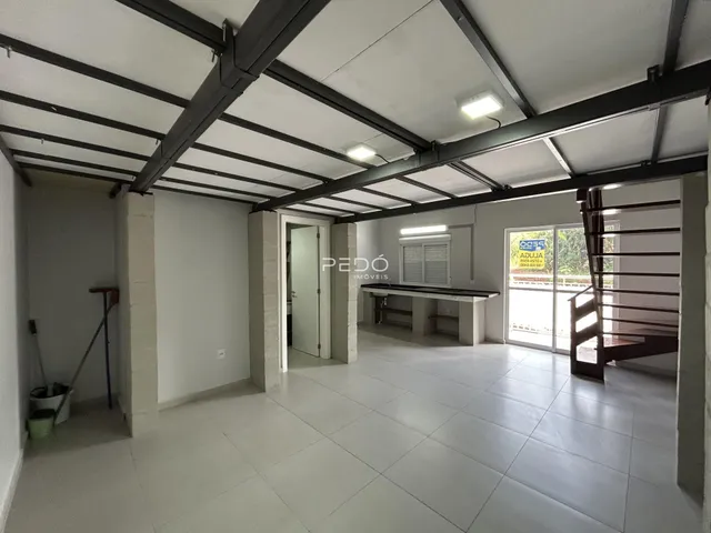 Espaço interno com teto de estrutura metálica exposta e piso de cerâmica.