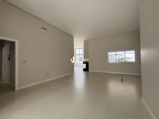 Interior de uma sala ampla com piso de cerâmica e paredes brancas.