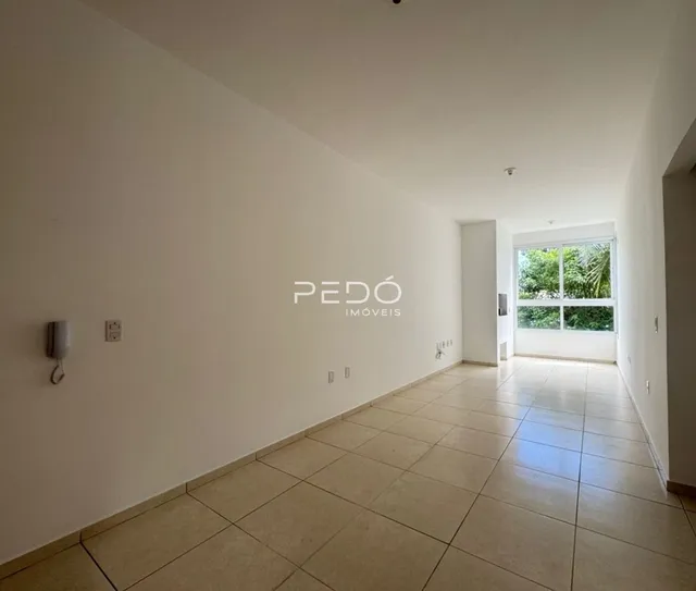 Corredor interno de uma residência com paredes brancas e piso de cerâmica clara.