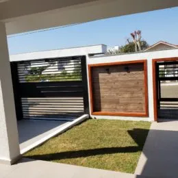 Vista externa com piso claro e área gramada.