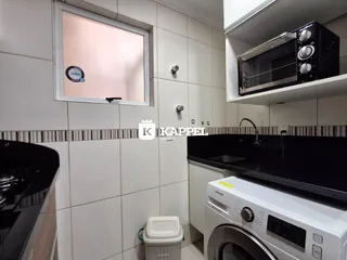 Vista parcial de uma cozinha com revestimento de azulejos brancos e eletrodomésticos modernos.