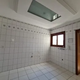 Interior de um cômodo com revestimento de azulejos brancos nas paredes e piso.