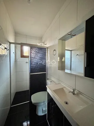 Foto de um banheiro com revestimento de azulejos brancos e piso escuro.