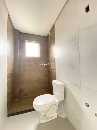 Foto de um banheiro interno com revestimento de parede em tons de marrom e branco.