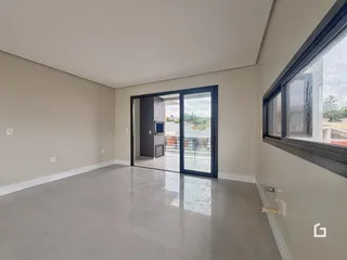Ambiente interno de uma sala ampla com piso de concreto polido e porta de vidro.