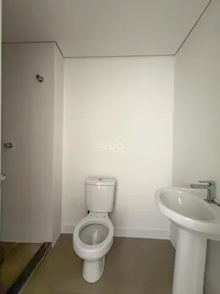 Foto interna de um banheiro com vaso sanitário e pia brancos.
