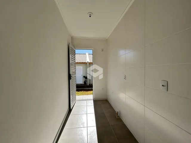 Corredor interno com piso claro e paredes brancas.