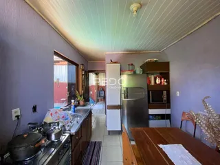Vista interna de uma cozinha com armários e eletrodomésticos em uma residência.