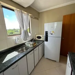 Vista de uma cozinha com armários brancos e bancada escura em um imóvel em Lajeado.