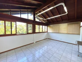 Ambiente interno de uma sala com teto de madeira e grandes janelas.