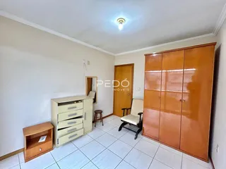 Quarto com armário de madeira e piso de cerâmica.